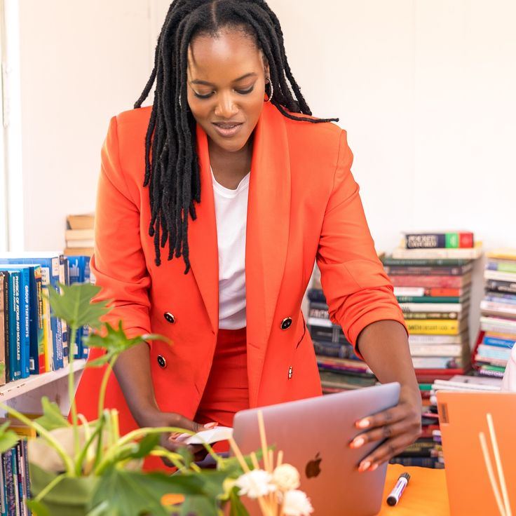 Entrepreneure en veste orange pilotant son activité depuis son ordinateur